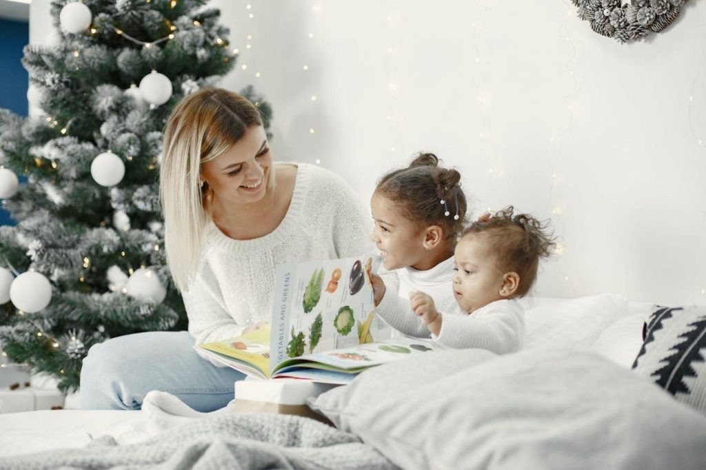 Mother with two children reading a book on a bed