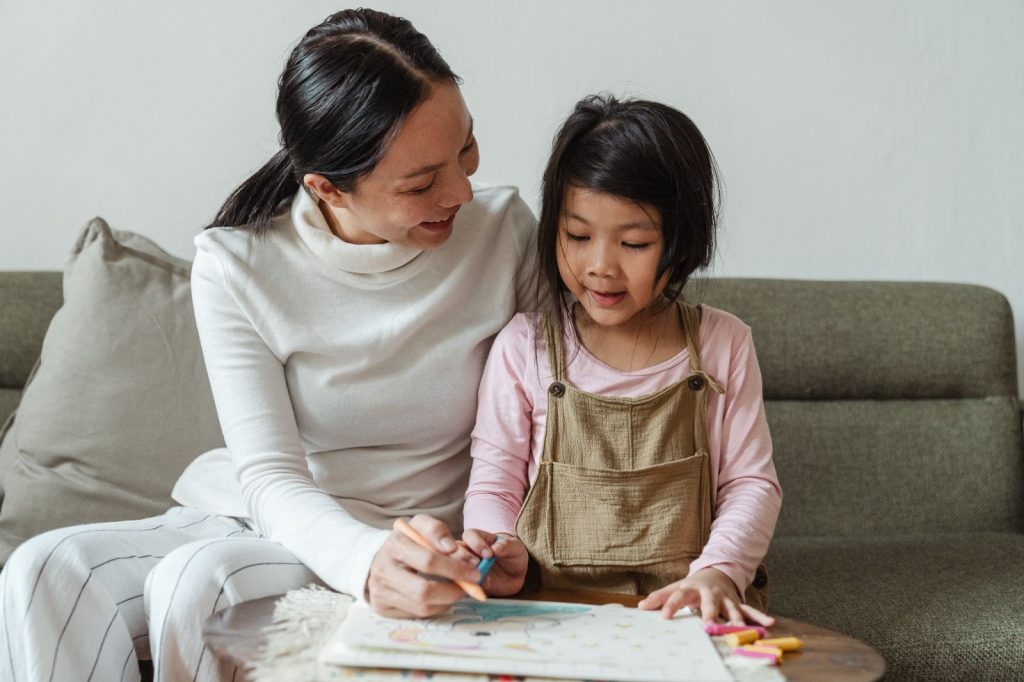 Smiling parent teaching a child to draw