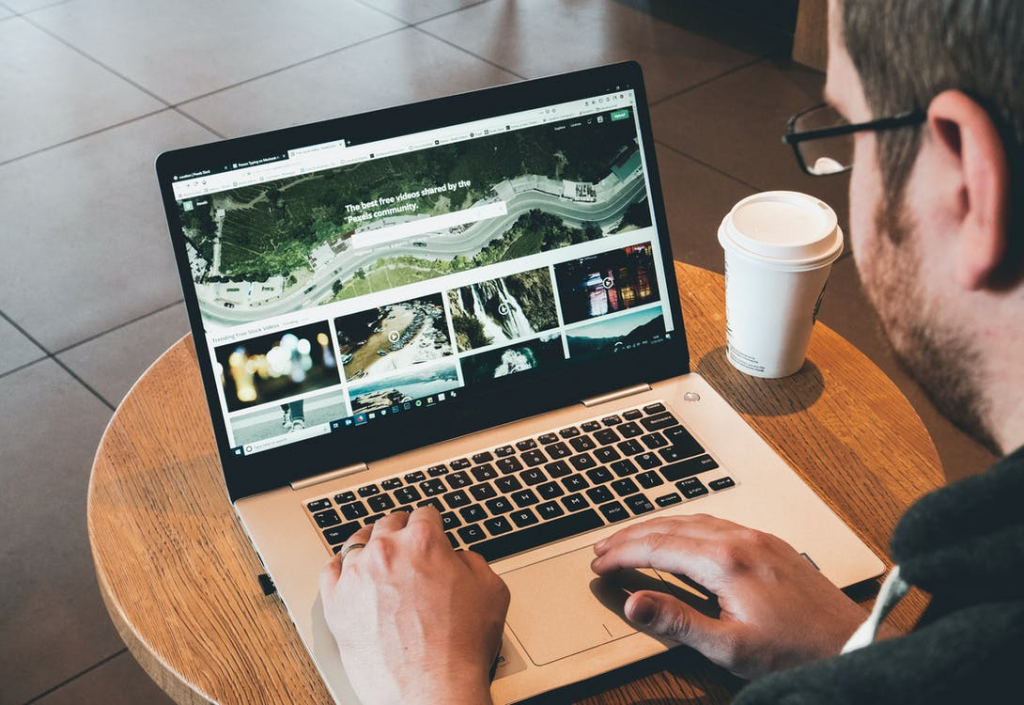 A man using a laptop and drinking coffee