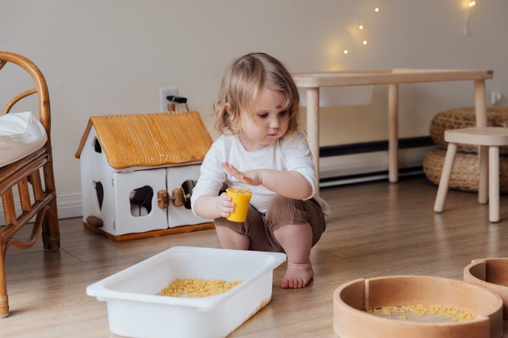 A girl holds a cupful of macaroni