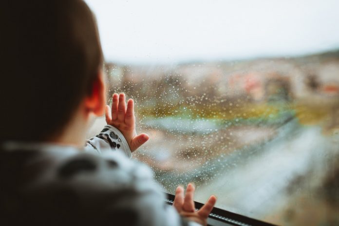 Toddler staring outside through a window