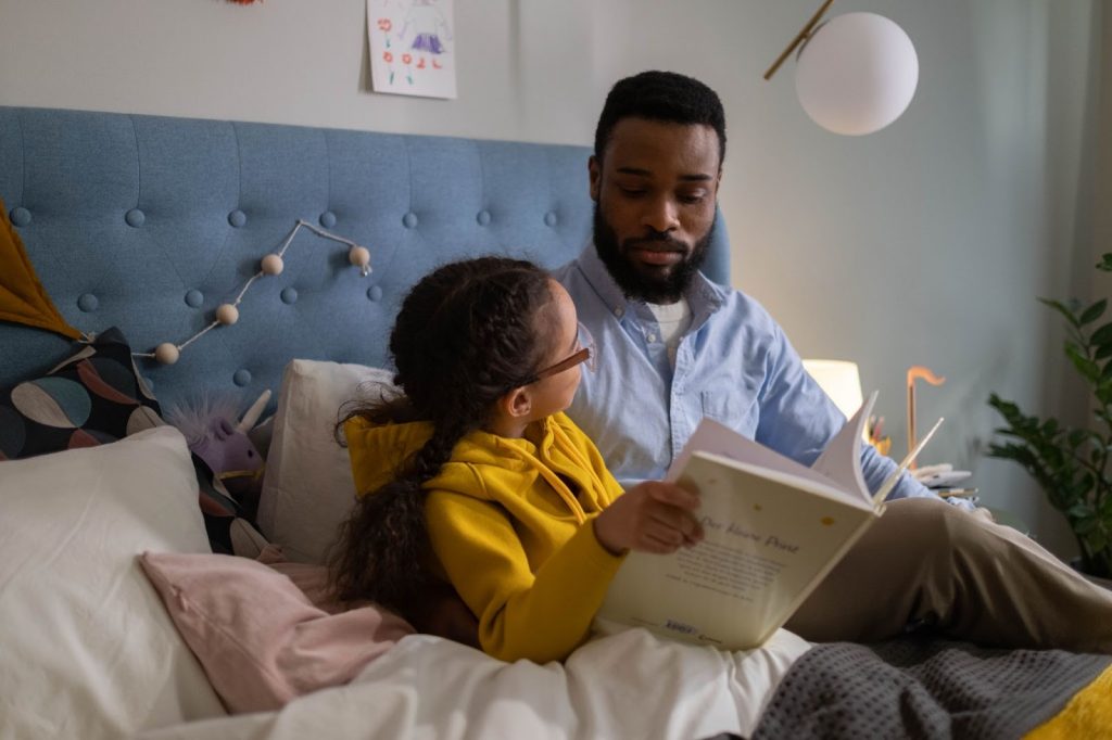 A little girl reading a storybook with her father