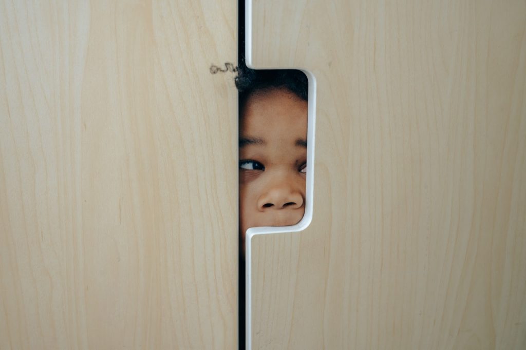 Young girl hidden in a closet peers outside