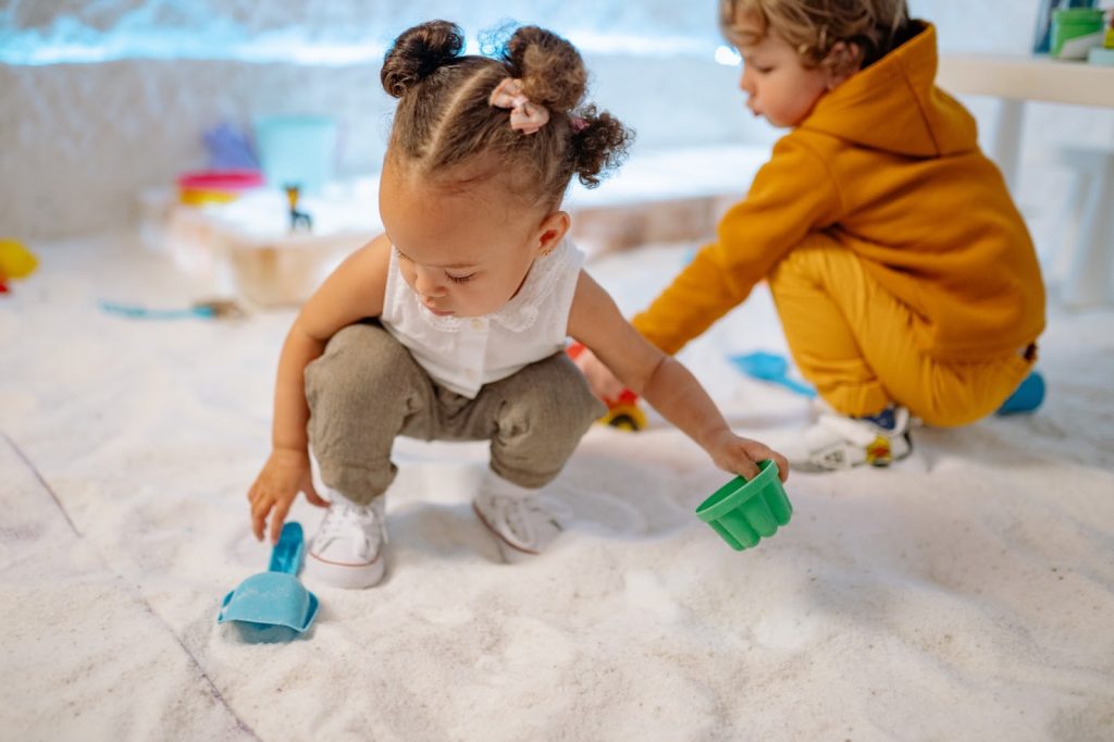 Crouching toddlers playing with sand