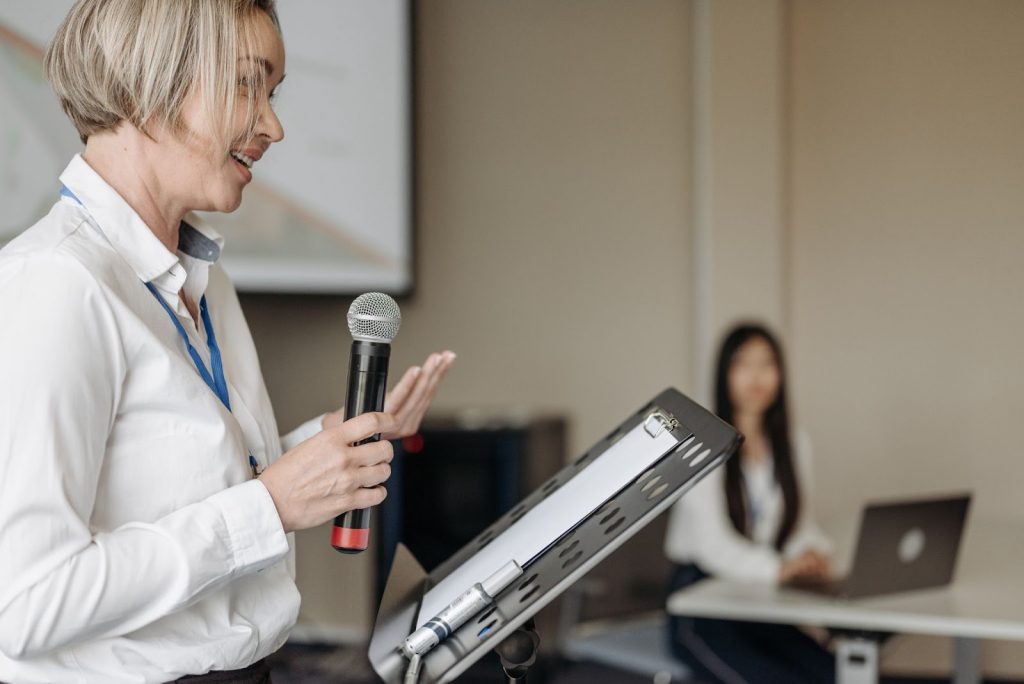 A woman standing with a microphone and speaking