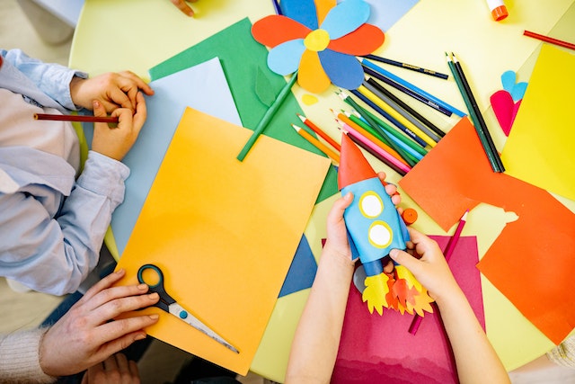 Children using construction paper to create a rocket ship