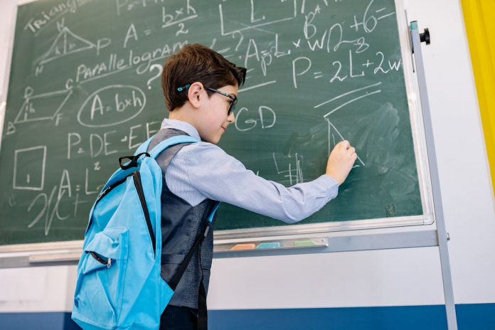 A boy texting on black board in the classroom