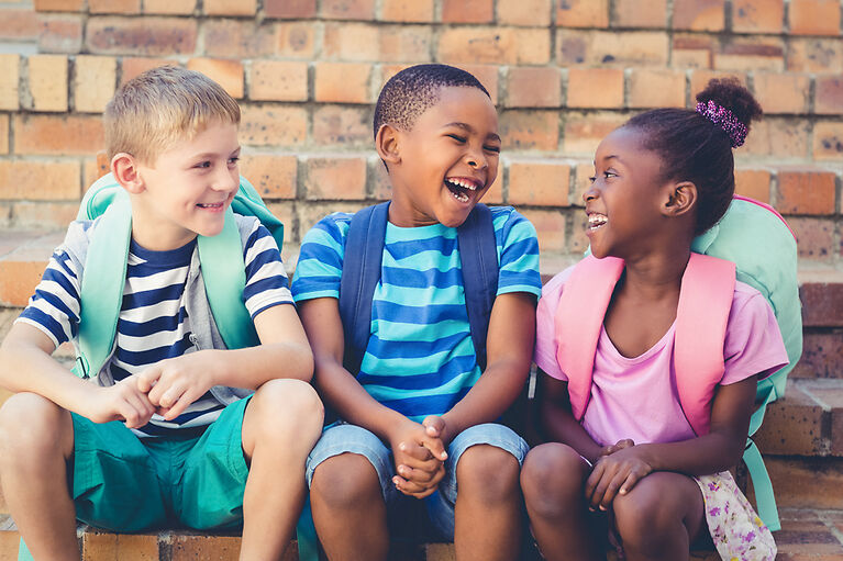 Happy school kids sitting together and laughing