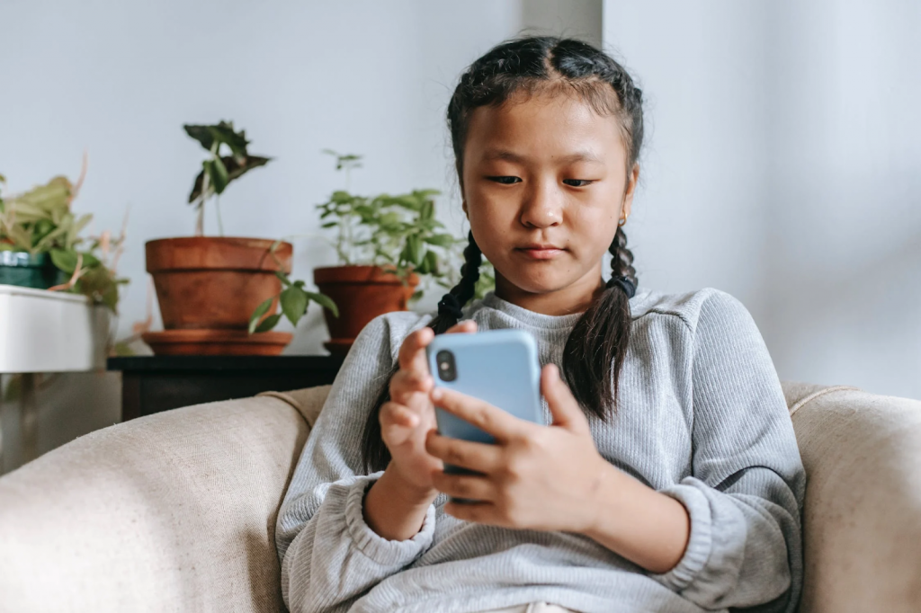 A young girl uses a smartphone on the couch