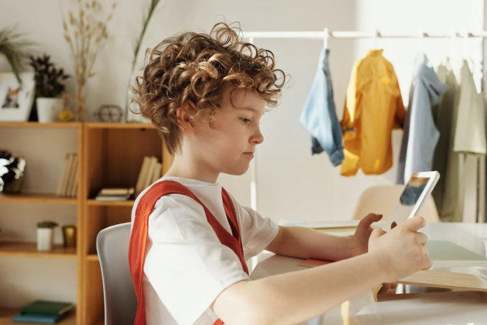 A kid uses a tablet on their study table