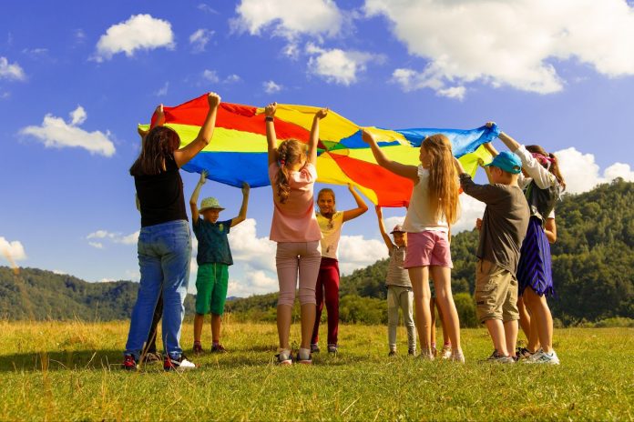 Kids playing with large, colorful sheet in a park