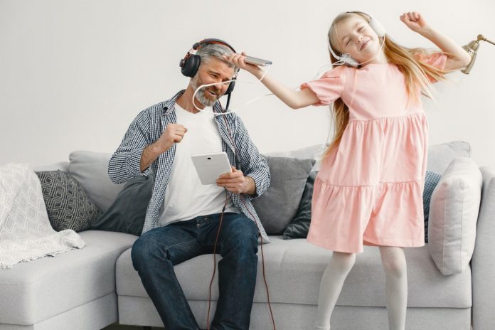 A father and his daughter enjoy music in the living room