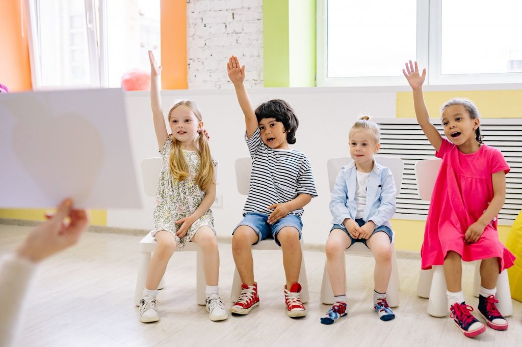 Children raising hands to answer in class
