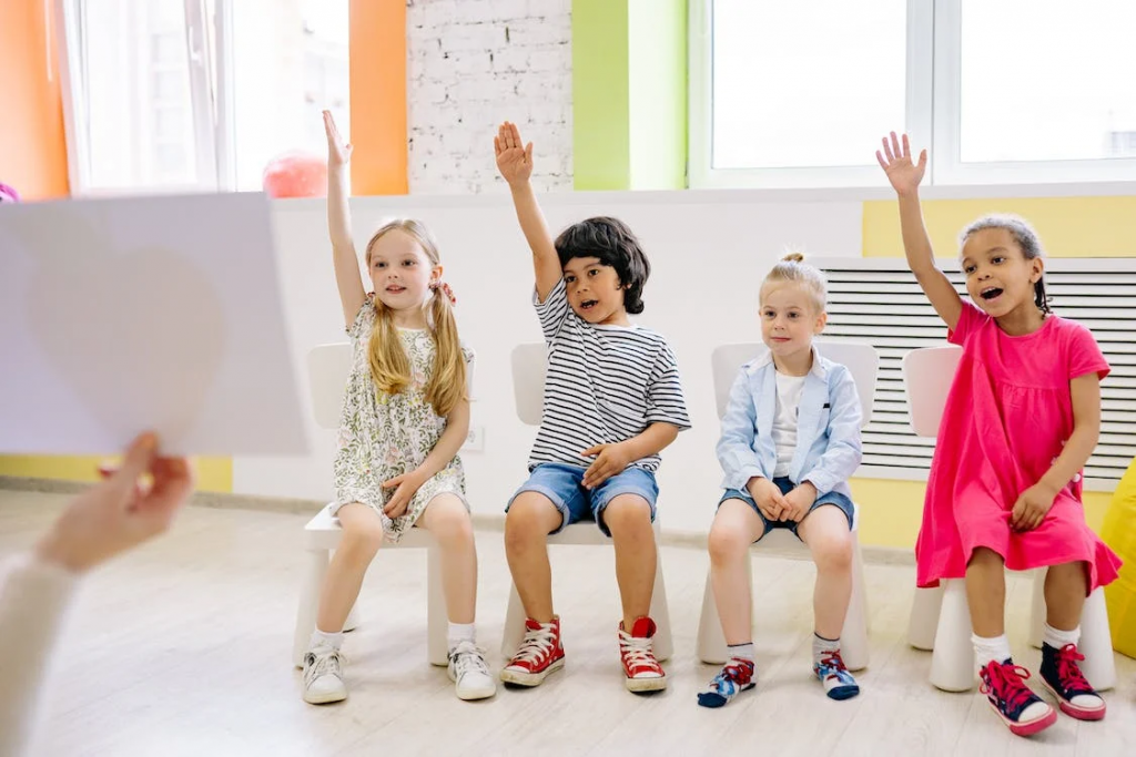 Kids are in the classroom with hands-up posture