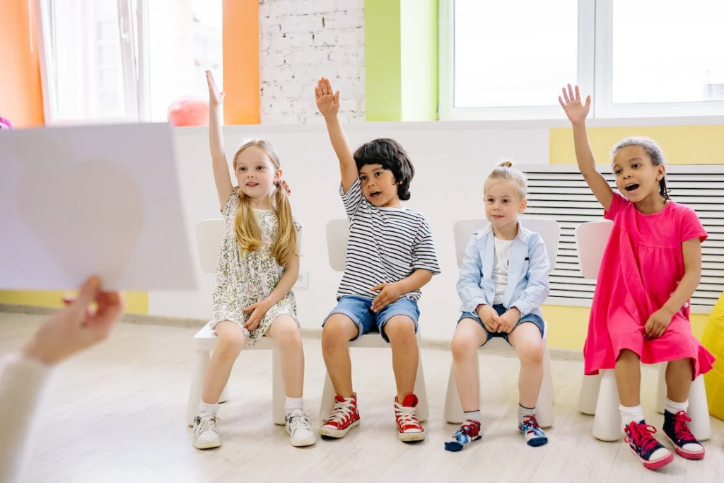 Kids are in the classroom with hands up posture