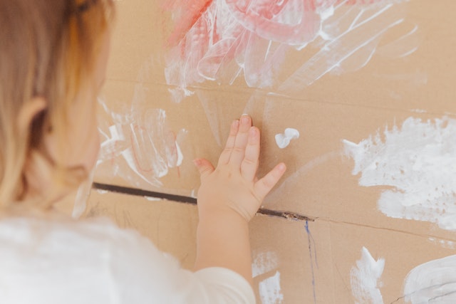 A child finger painting a cardboard box