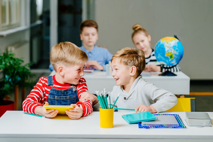 Two kids talking and chuckling in a classroom