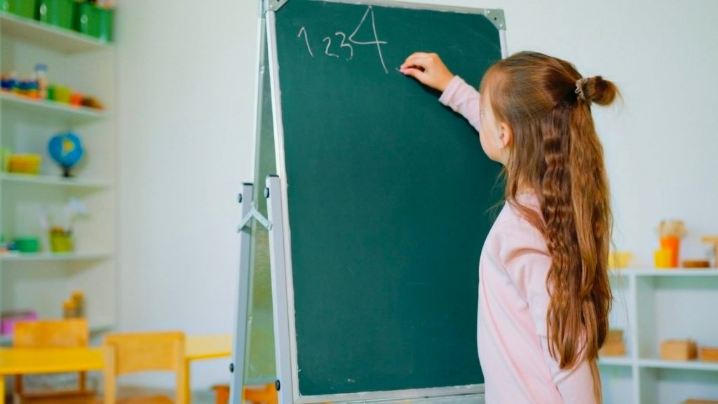 Student writing numbers on a blackboard