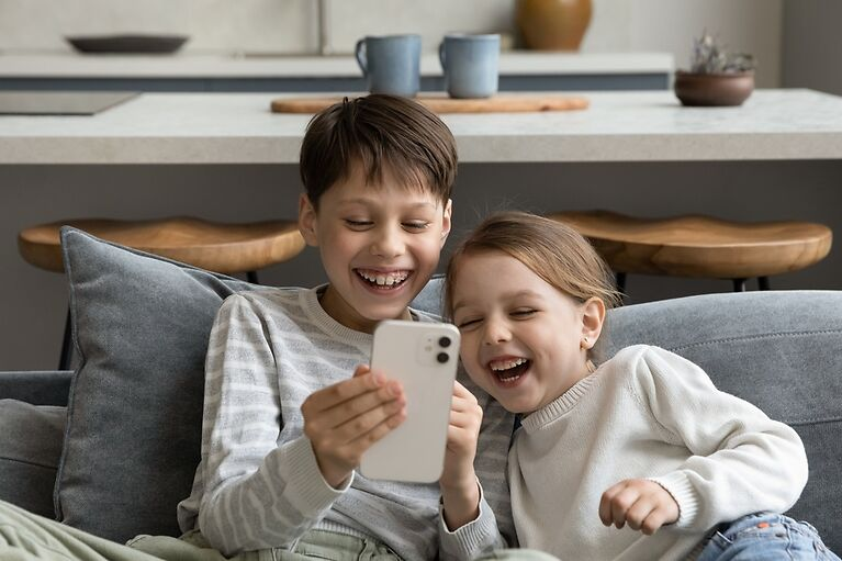 Siblings looking at a phone screen and laughing