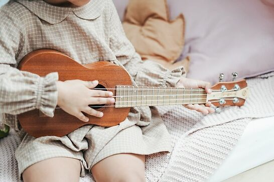 Young girl playing ukulele on a sofa