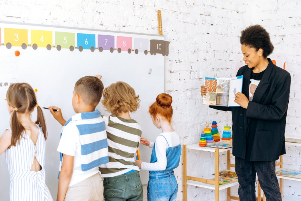 Kids and teacher in the classroom with white board