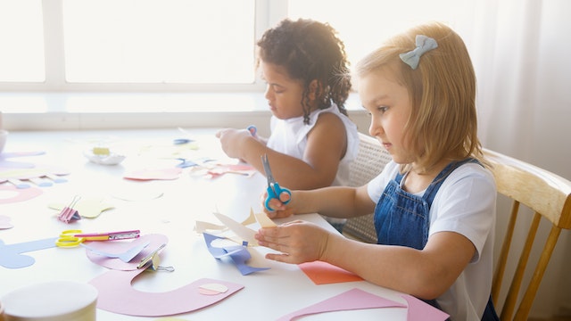 Two girls cutting up paper into fun different shapes