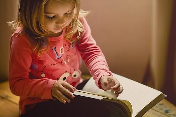 Little girl sitting and reading a book