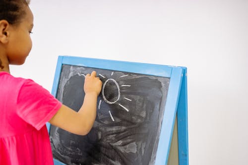 A toddler drawing on a blackboard