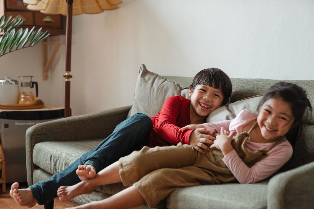 Photo of two kids having fun while sitting on gray couch