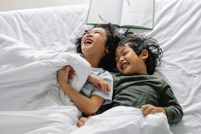 Kids lying in bed and laughing