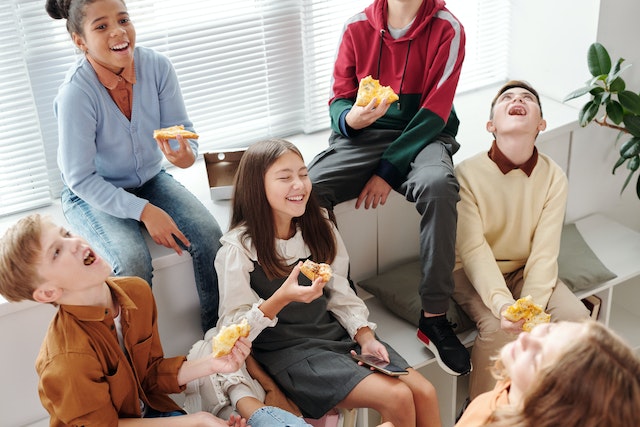Kids sitting in a group and eating slices of pizza