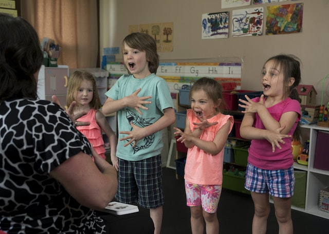 Four kids standing in a row and acting