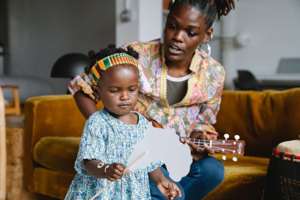 Mother playing ukelele and her daughter reciting rhyme