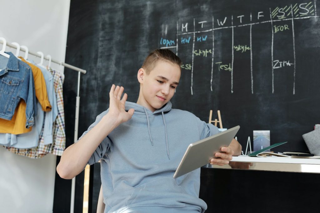 Photo of a boy wearing a gray hoodie while using tablet