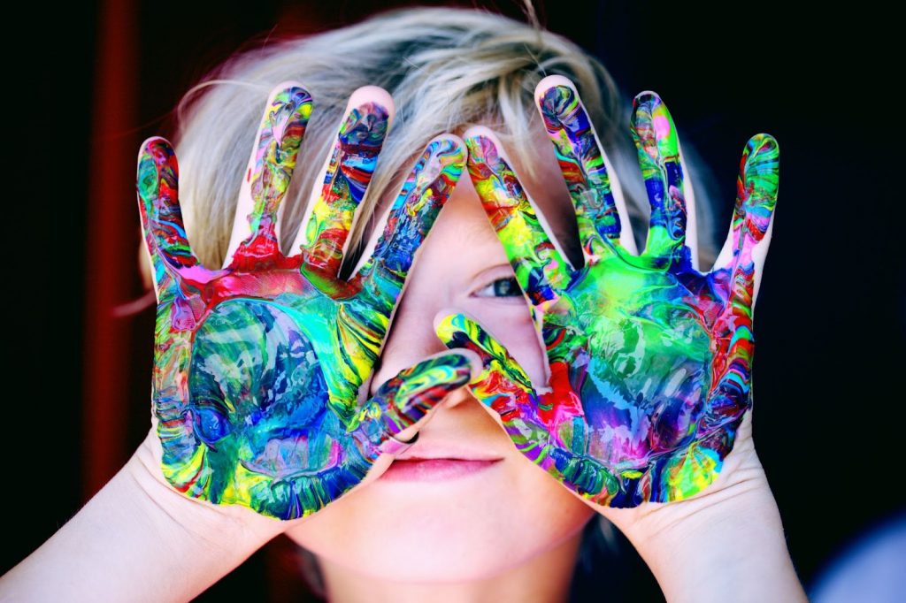 Little girl with multicolor paint on her hands