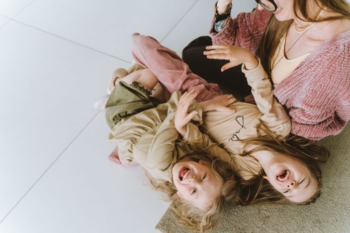 Photo of Siblings Laughing Beside Their Mother