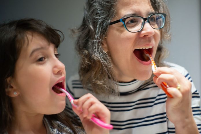 Mother and daughter brushing teeth together