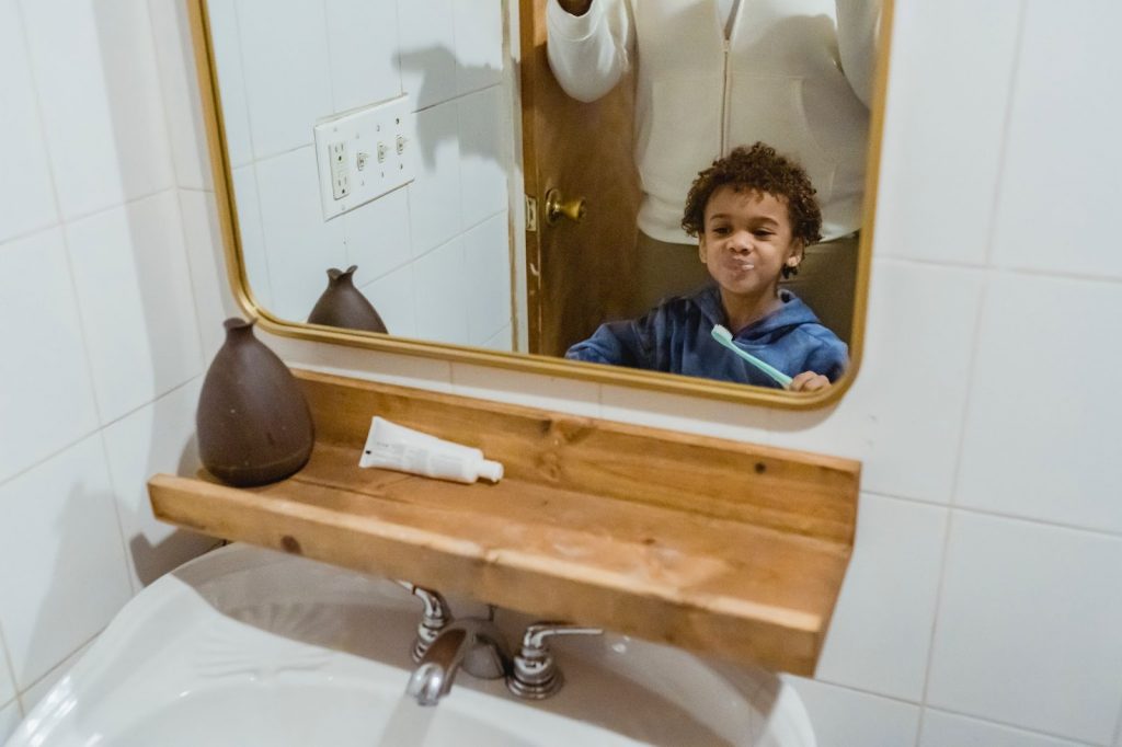 Boy brushing teeth with his parent