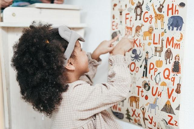 A little girl pointing an alphabet chart with pictures