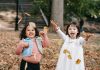 Two happy girls throwing foliage in the park