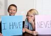 Boy and girl holding cards with I have Never writtten on them