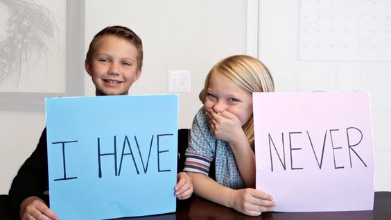 Boy and girl holding cards with I have Never writtten on them