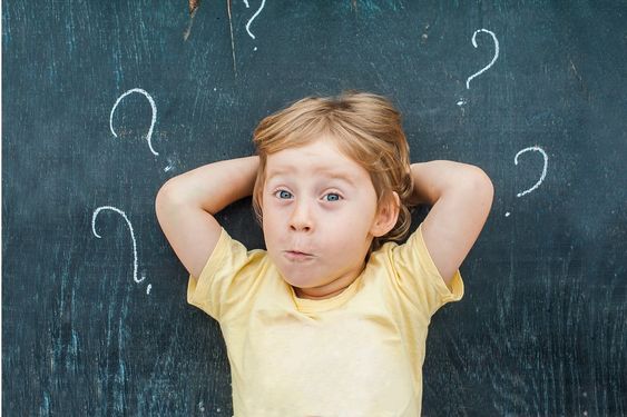 Boy infront of blackboard with questions marks