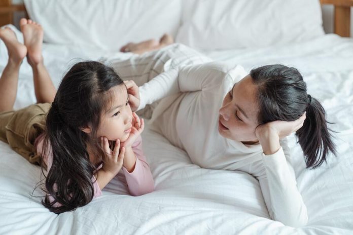 Mom and daughter talking while lying on bed
