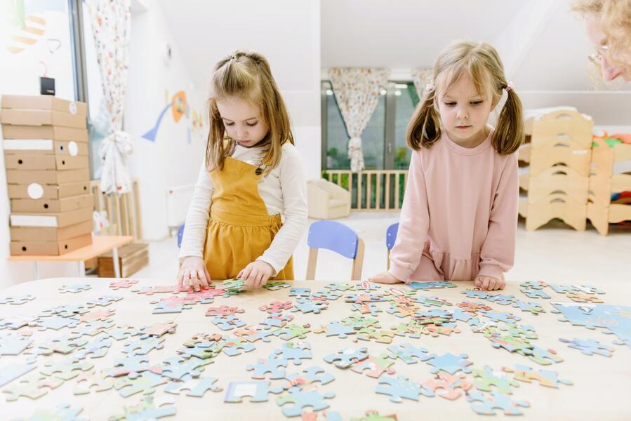 Two little girls playing with jigsaw puzzle