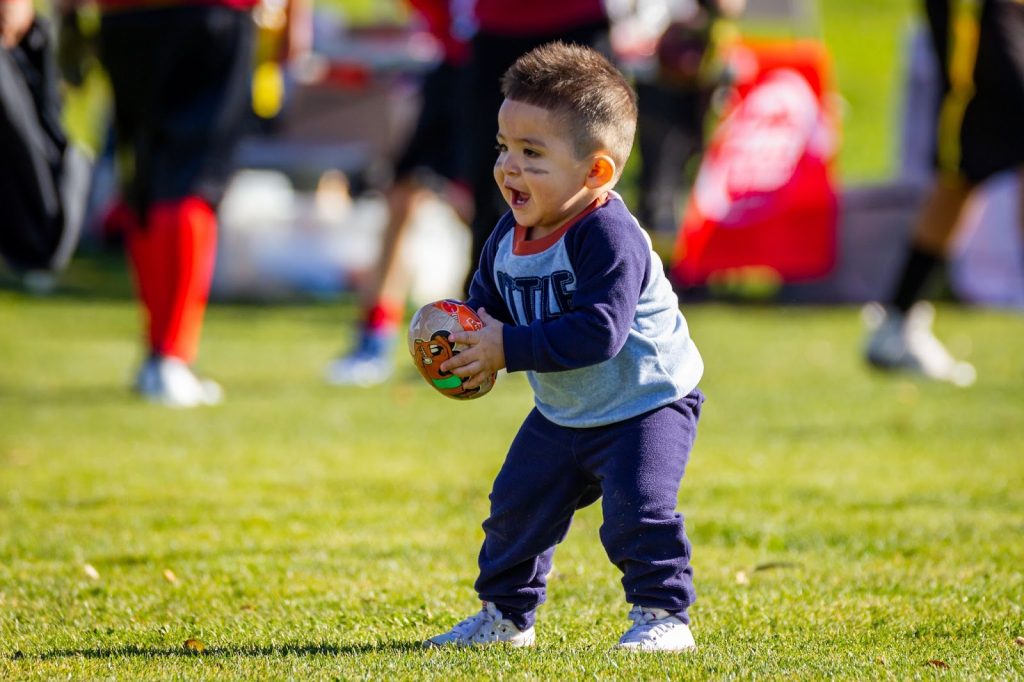 Little boy in a field holding rugby ball