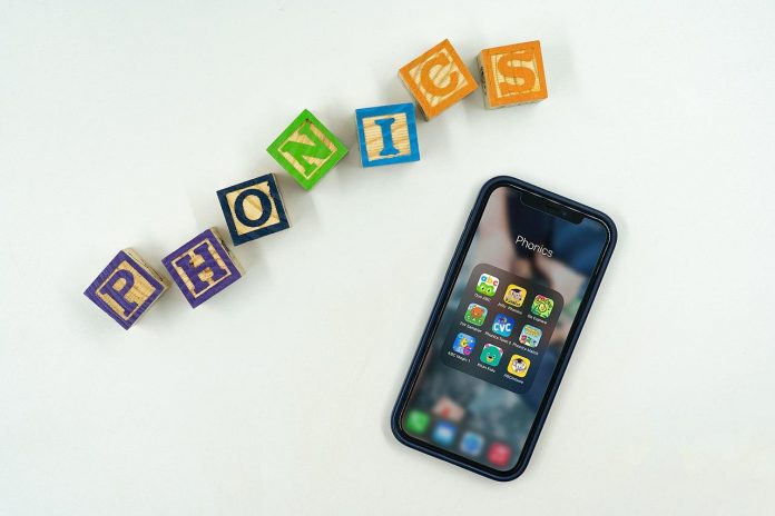 The word ‘phonics’ written using wooden blocks and phonics games and apps displayed in phone