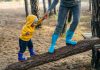 Mother holding hand of her kid standing on wooden log