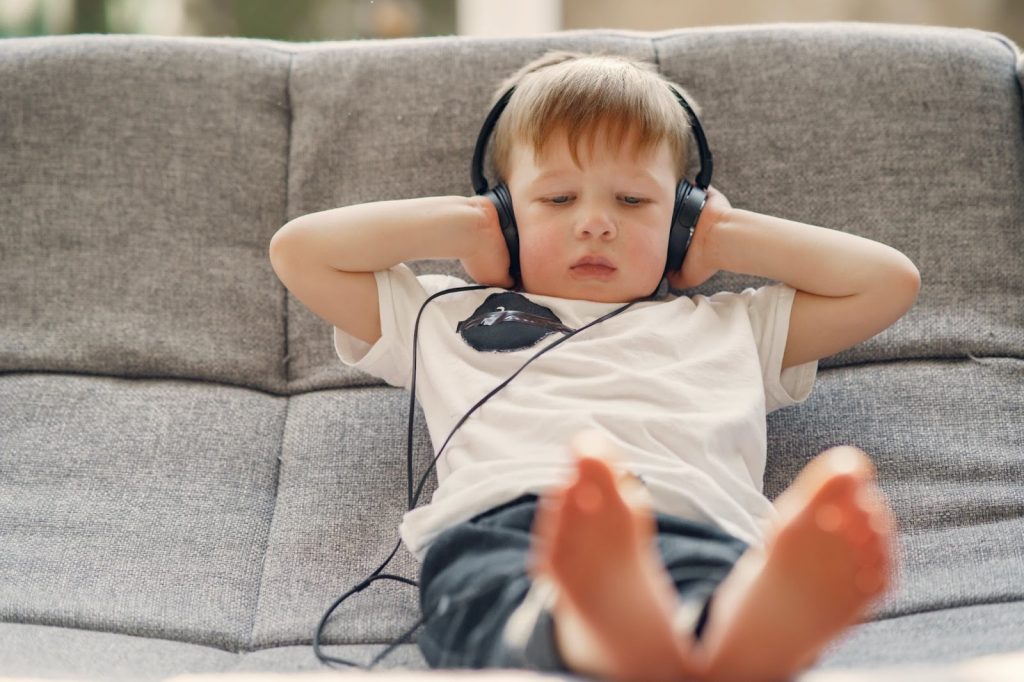 Young boy with headphones on relaxes on a couch