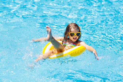 Little girl in swimming pool with floaters enjoying summers